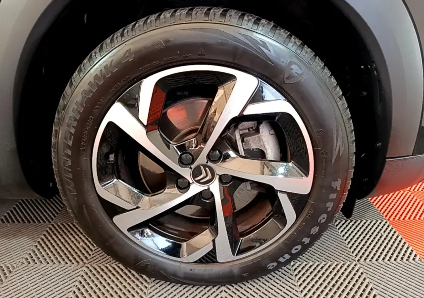 Gros plan sur la roue avant gauche du Citroën C5 Aircross Hybrid 225 ë-EAT8 Shine noir, jante alliage bicolore.