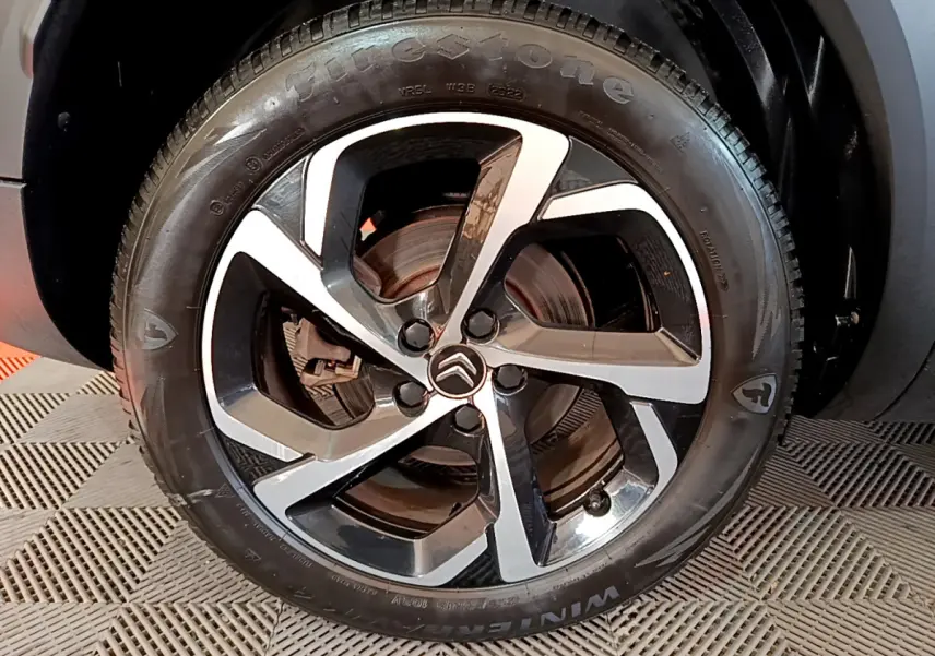 Gros plan sur la jante alliage bicolore et le pneu Firestone d'un Citroën C5 Aircross Hybrid noir, côté arrière.