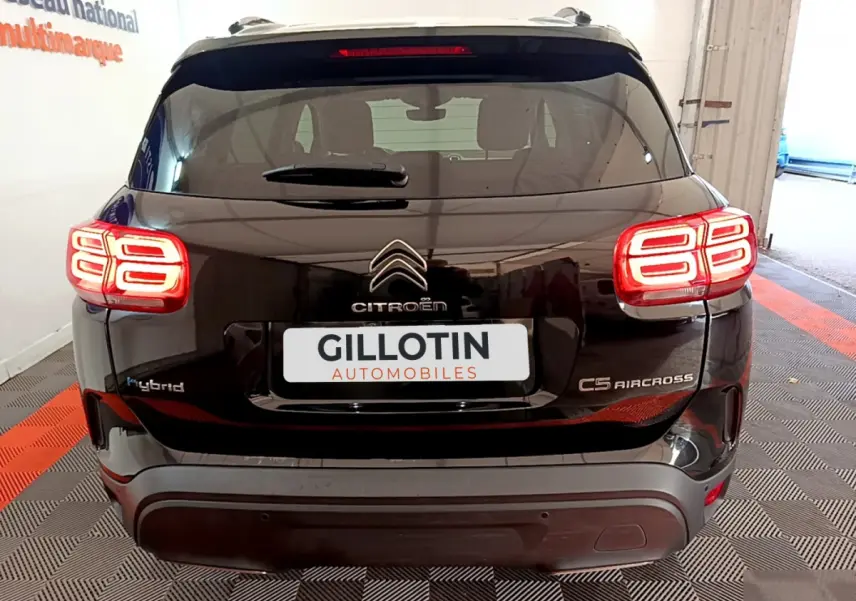 Vue arrière d'un Citroën C5 Aircross Hybrid noir avec feux LED caractéristiques allumés en intérieur showroom.