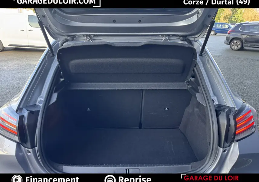 Coffre ouvert vu de l'arrière d'une Peugeot 208 Hybrid 110 gris clair, feux arrière LED visibles.