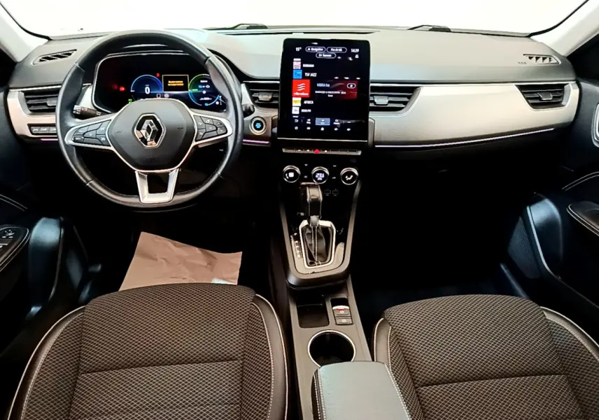 Vue intérieure avant du Renault Arkana Techno E-Tech 2023, tableau de bord noir avec écran tactile vertical et volant multifonctions.