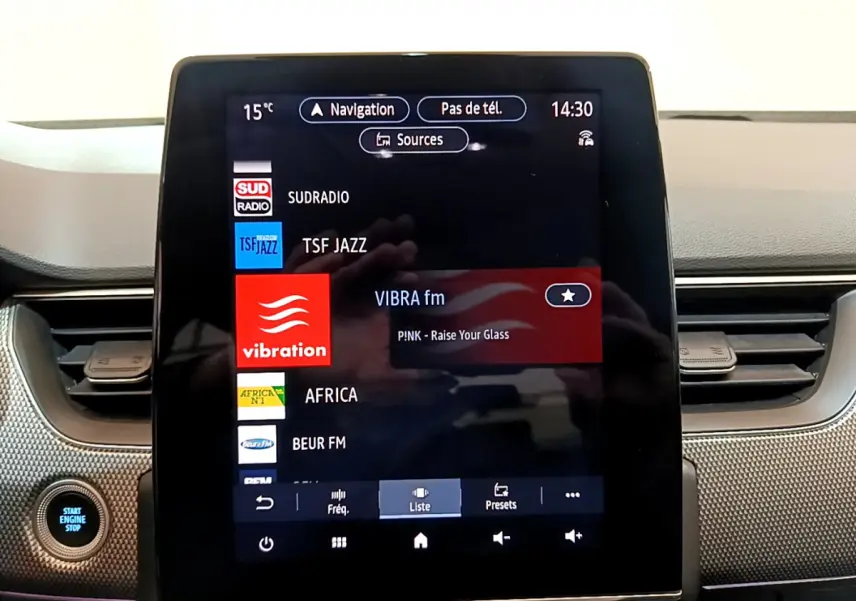 Écran tactile central de la Renault Arkana Techno E-Tech 145, affichant les stations radio, avec bouton démarrage visible à gauche.