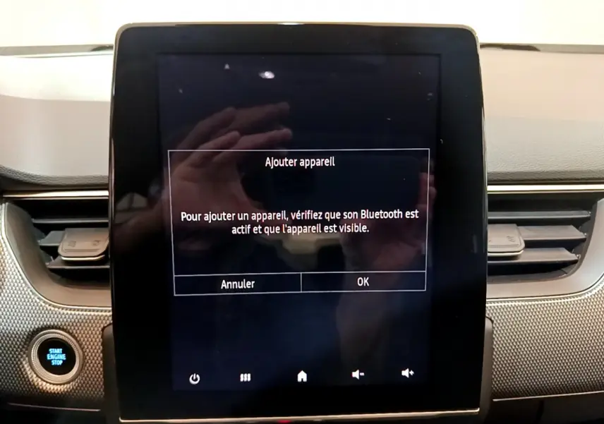 Écran tactile central allumé avec message Bluetooth, tableau de bord gris et bouton démarrage dans Renault Arkana bleu.