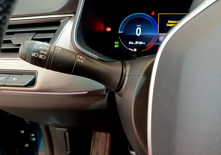 Gros plan sur le combiné d'instruments numérique bleu et le commodo des phares du tableau de bord du Renault Arkana Techno E-Tech 2023.