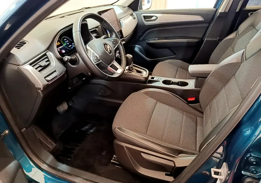 Vue intérieure côté conducteur de la Renault Arkana bleu 2023, avec tableau de bord numérique et sièges tissu gris.
