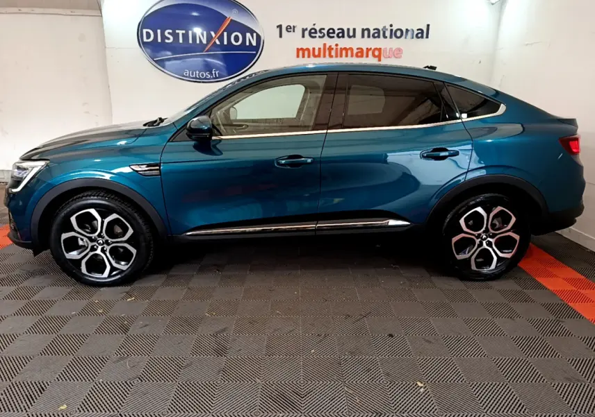 Profil côté gauche d’un Renault Arkana bleu 2023 avec jantes alliage et ligne de toit plongeante.