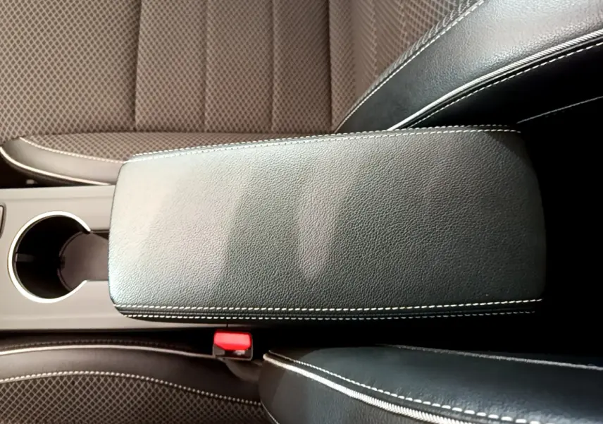 Détail de l'accoudoir central en cuir noir avec surpiqûres blanches et sièges tissu marron du Renault Arkana 2023.