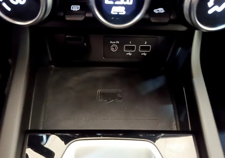 Gros plan sur la console centrale noire du Renault Arkana Techno E-Tech 2023 avec ports USB et zone de recharge sans fil.