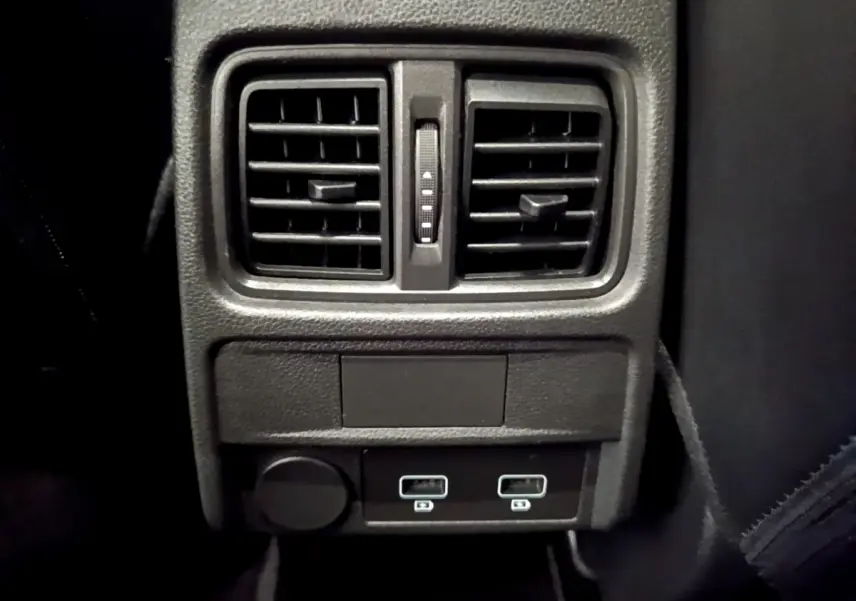 Vue rapprochée de la console arrière noire avec bouches d’aération et deux ports USB du Renault Arkana bleu 2023.