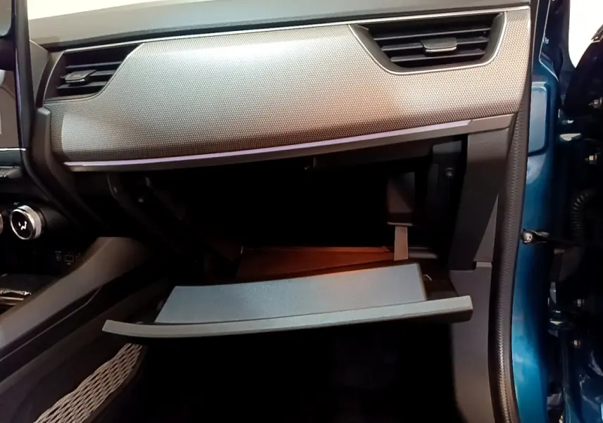 Vue intérieure côté passager du coffre à gants ouvert d’un Renault Arkana bleu, soulignant la finition moderne du tableau de bord.