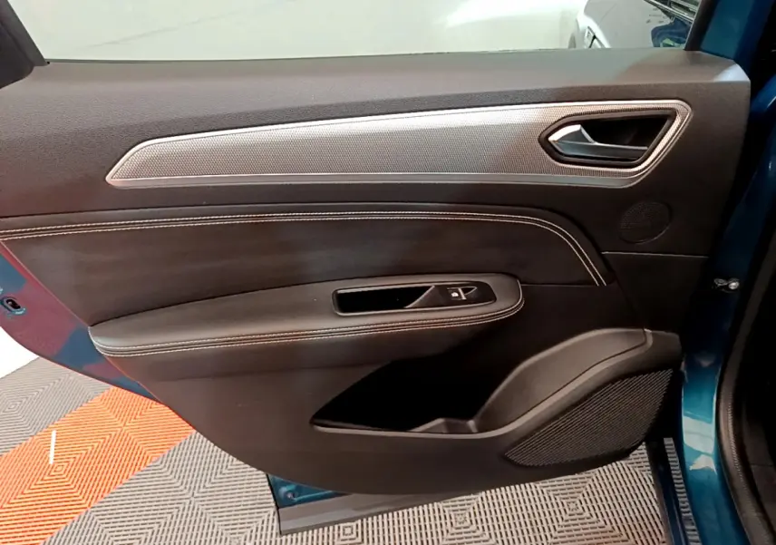 Vue intérieure côté gauche de la porte avant d’un Renault Arkana bleu, avec garniture noire et insert argenté.