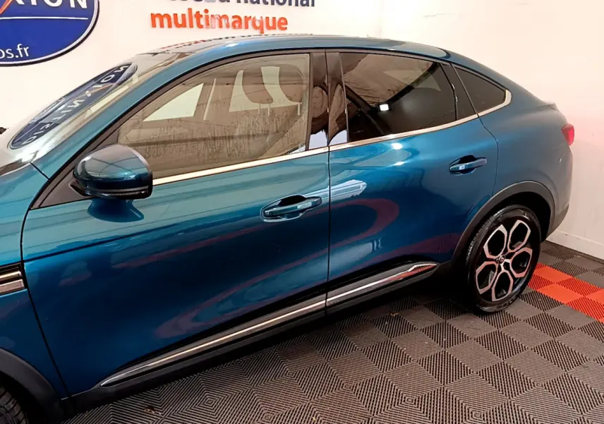 Vue latérale droite d’un Renault Arkana bleu 2023 avec jantes distinctives et vitres teintées.