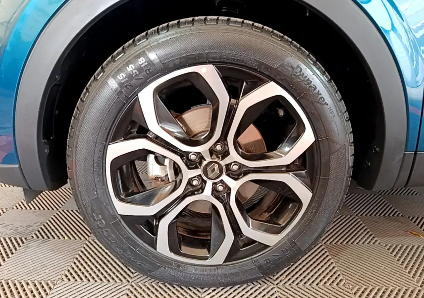 Gros plan sur la roue avant droite du Renault Arkana bleu 2023 avec jante alliage bicolore et logo Renault central.