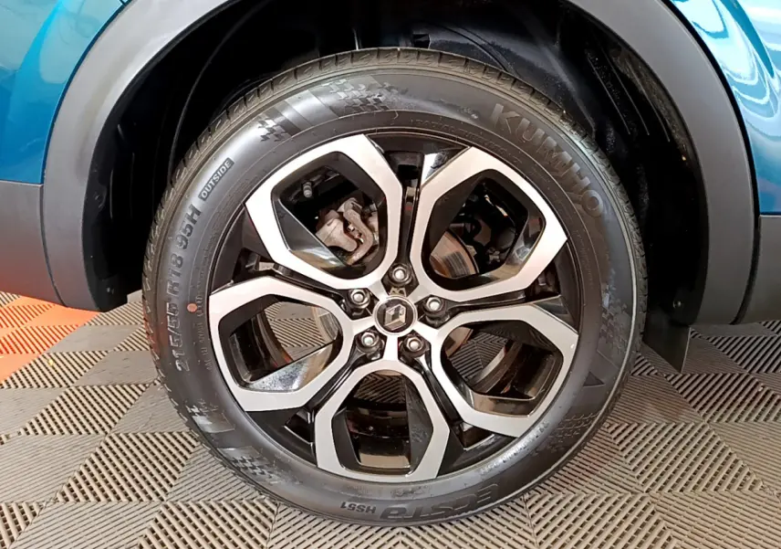 Gros plan sur la roue avant droite du Renault Arkana bleu 2023 avec jante alliage noire et argentée.