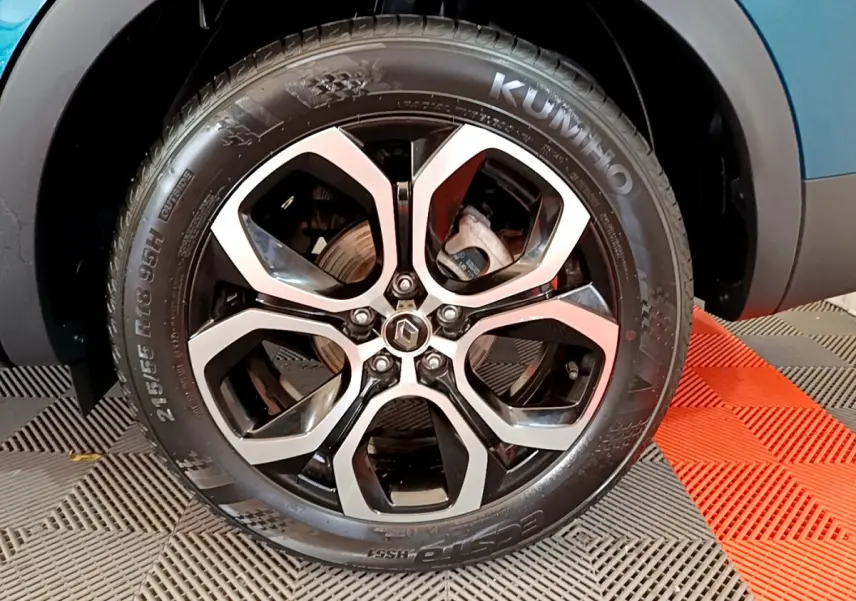 Gros plan sur la roue avant gauche du Renault Arkana bleu, mettant en valeur la jante alliage noire et argentée.