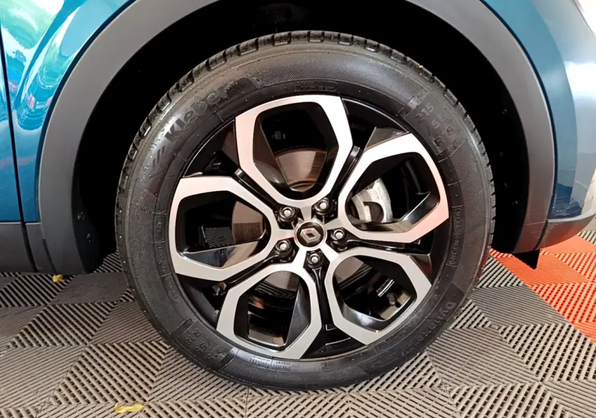 Gros plan sur la roue avant droite d’un Renault Arkana bleu, mettant en valeur la jante alliage moderne.
