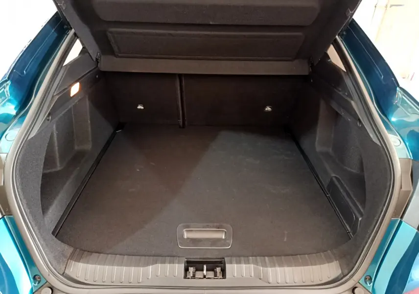 Coffre ouvert vu de l'arrière d'un Renault Arkana bleu, montrant un espace de chargement spacieux et propre.