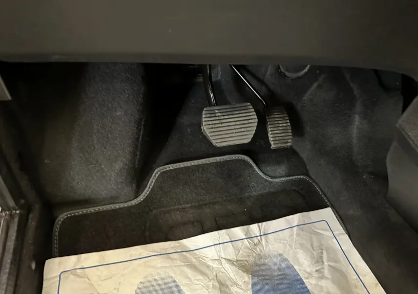 Gros plan sur les pédales et tapis noirs de l'AIXAM AMBITION 0.5 CITY COUPE GTI E5+ 2025, sans vue extérieure du véhicule.