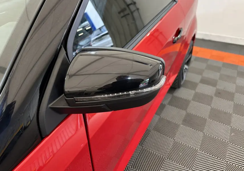 Gros plan sur le rétroviseur extérieur côté conducteur noir brillant de l'AIXAM AMBITION rouge 2025.