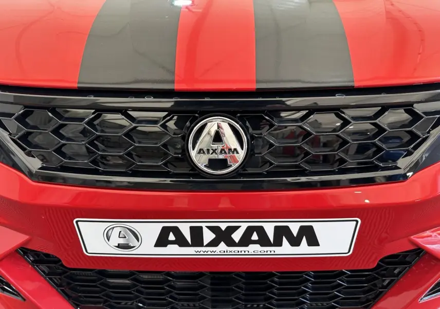 Gros plan sur la calandre noire et le logo AIXAM d'une AMBITION rouge avec bandes noires sur le capot.