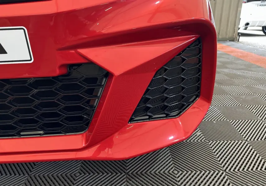 Gros plan sur la calandre avant rouge de l'AIXAM AMBITION 0.5 CITY COUPE GTI E5+ avec grille noire hexagonale.