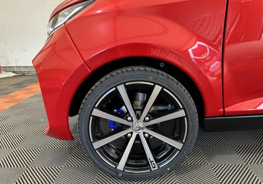 Gros plan sur la roue avant gauche rouge d'une Aixam Ambition 0.5 City Coupe GTI avec jante noire et détails gris.