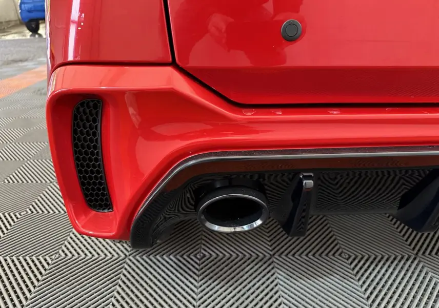 Gros plan sur le pot d’échappement et le diffuseur arrière noir d’une Aixam Ambition rouge côté gauche.