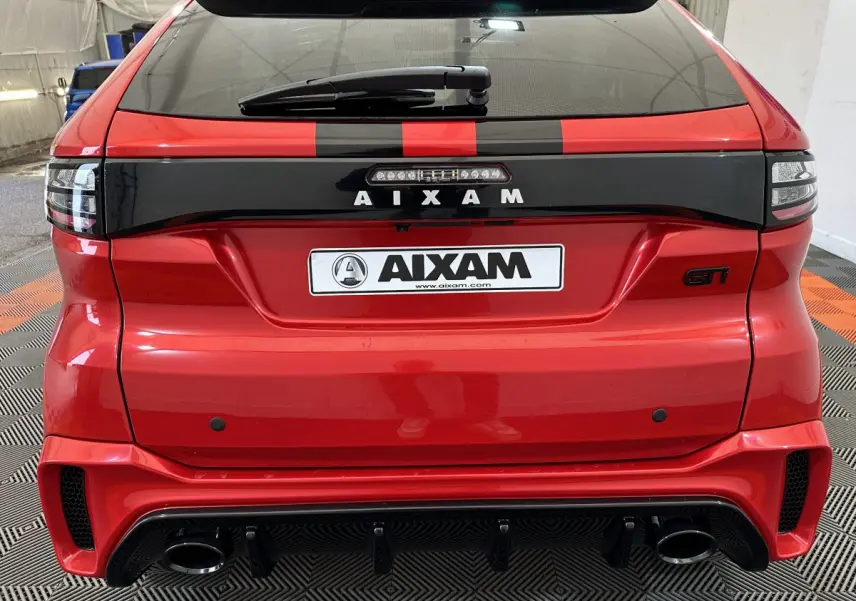 Vue arrière d'une Aixam Ambition rouge avec bande noire et logo GTI, détails sportifs et feux modernes.