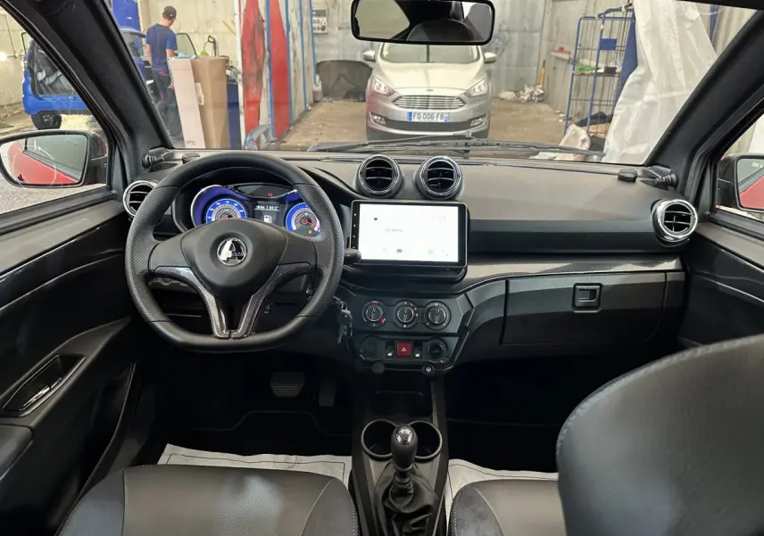 Vue intérieure de l'AIXAM AMBITION 0.5 CITY COUPE GTI E5+ 2025, tableau de bord et volant noir avec écran tactile central.