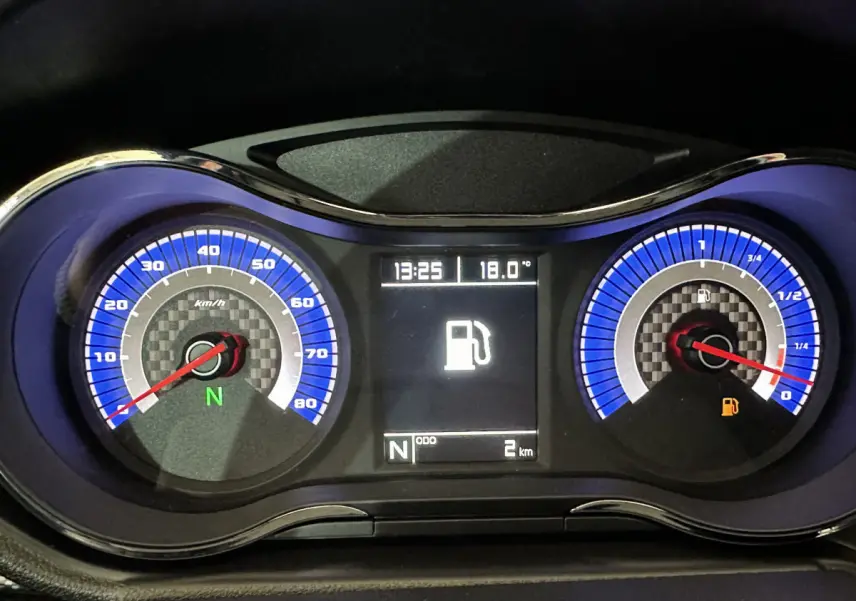 Tableau de bord de l'AIXAM AMBITION rouge 2025 montrant compteur vitesse, jauge carburant et écran digital central.
