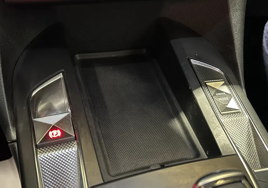 Gros plan sur la console centrale noire du DS3 Crossback, avec boutons frein à main électronique et mode de conduite.
