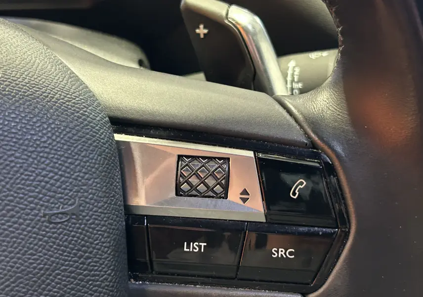 Gros plan sur les commandes noires et argentées du volant côté gauche du DS3 Crossback Bleu Millenium, avec molette et bouton téléphone.