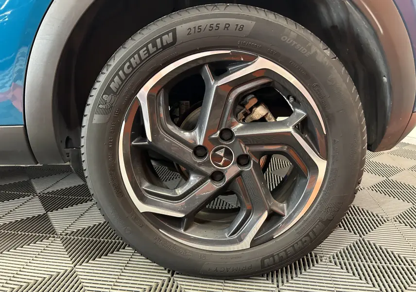 Gros plan sur la roue avant droite d’un DS3 Crossback Bleu Millenium avec jante alliage noire et argentée.