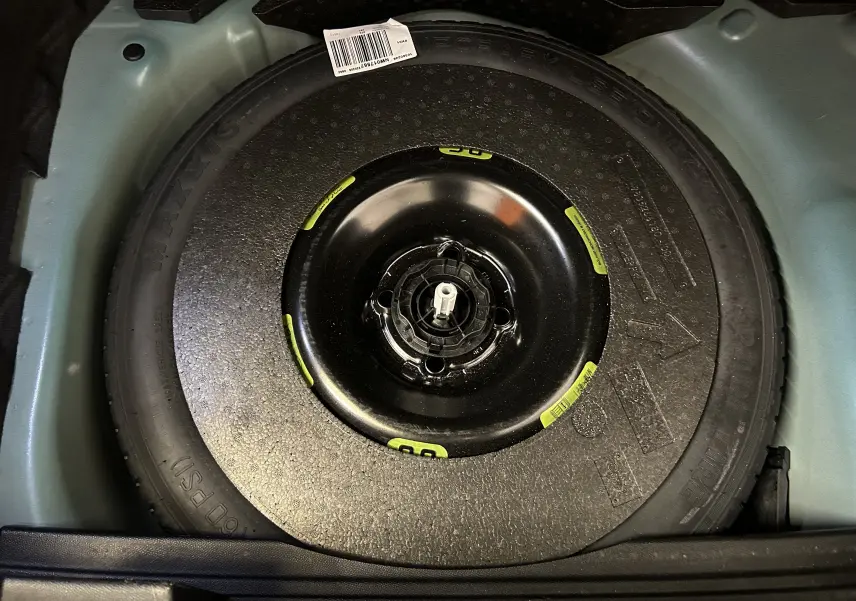 Roue de secours noire installée dans le coffre d’un DS3 Crossback Bleu Millenium, vue en plongée.