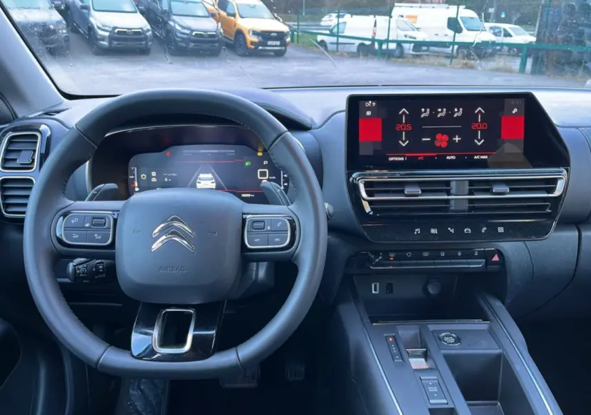 Vue intérieure du poste de conduite du Citroën C5 Aircross Hybrid blanc, avec volant multifonctions et écran tactile central.