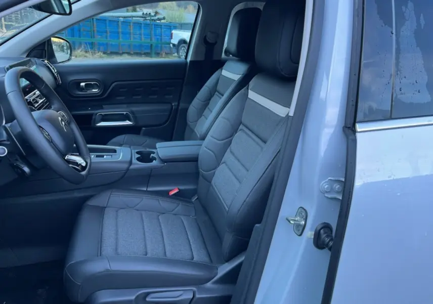 Vue intérieure côté conducteur du Citroën C5 Aircross blanc okénite, sièges avant en cuir et tissu gris avec accoudoir central.