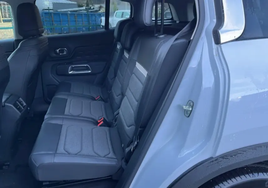 Vue intérieure côté droit montrant les trois sièges arrière individuels en tissu gris du Citroën C5 Aircross Hybrid blanc.