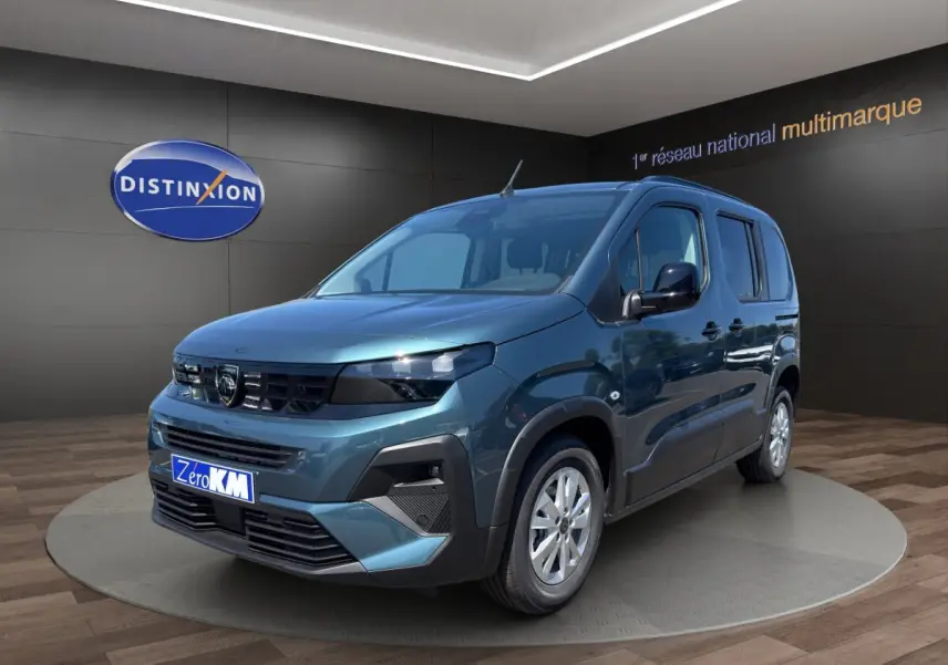 Peugeot Rifter bleu en vue 3/4 avant droit, avec calandre noire et jantes argentées, en showroom intérieur.