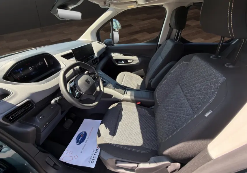 Vue intérieure côté conducteur du Peugeot Rifter 2026, sièges tissu gris et tableau de bord moderne avec écran tactile.