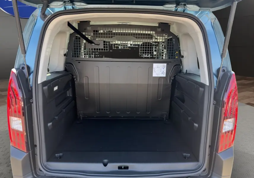 Vue arrière du coffre ouvert du Peugeot Rifter bleu, montrant la cloison de séparation métallique et l'espace de chargement vide.