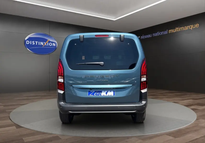 Vue arrière d'un Peugeot Rifter bleu 2026 dans un showroom avec logo Distinxion en arrière-plan.