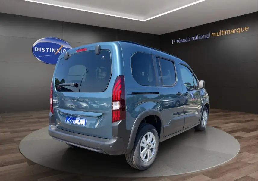 Peugeot Rifter bleu vue 3/4 arrière droit en intérieur, avec feux arrière verticaux et jantes argentées.