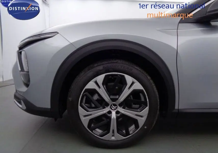 Gros plan sur la roue avant gauche et l'aile d'une Citroën C5 X gris Artense métal avec jante alliage distinctive.