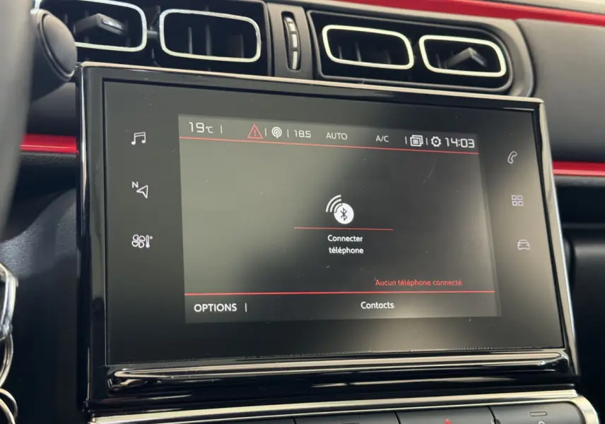 Écran tactile central en gros plan dans l'habitacle noir et rouge de la Citroën C3 PureTech 2019.