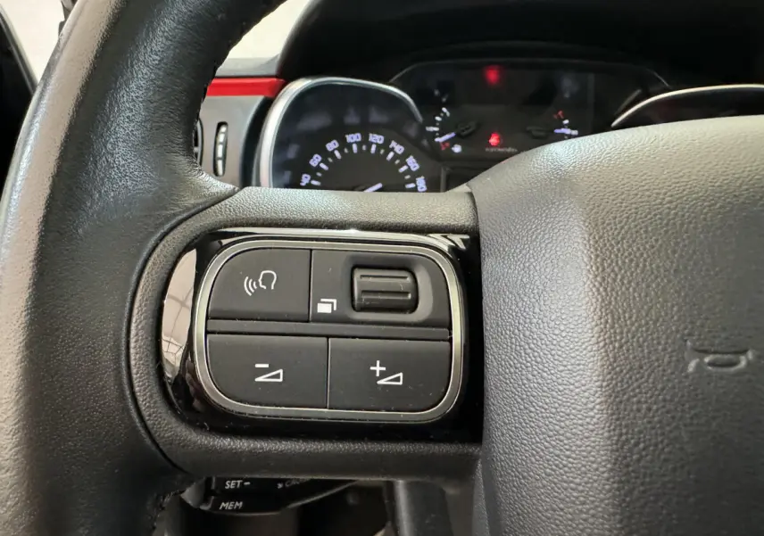 Gros plan sur les commandes gauche du volant cuir noir d'une Citroën C3 2019 PureTech Shine Business.