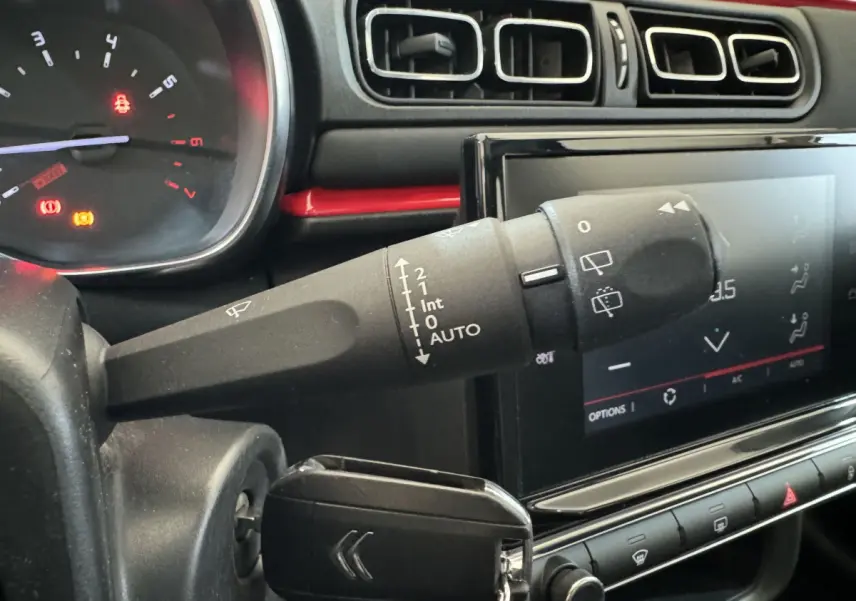 Gros plan sur la commande d’essuie-glace et l’écran tactile du tableau de bord noir d’une Citroën C3 2019 Shine Business.