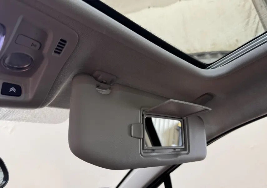 Détail intérieur montrant le pare-soleil avec miroir ouvert et toit ouvrant du Citroën C3 noir, version Shine Business.