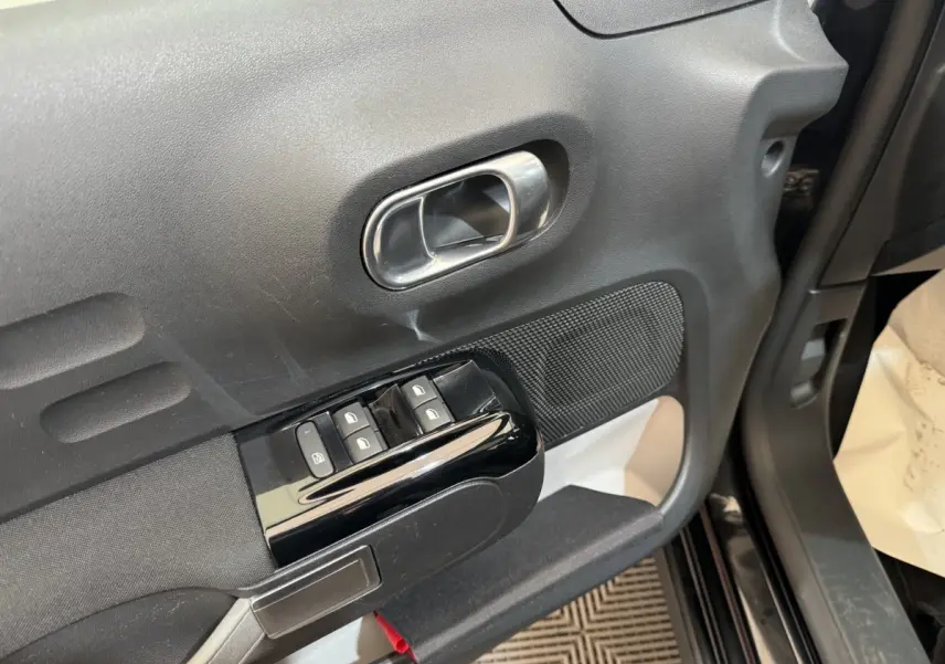 Poignée de porte intérieure côté conducteur de Citroën C3 noire, avec commandes de vitres et verrouillage.