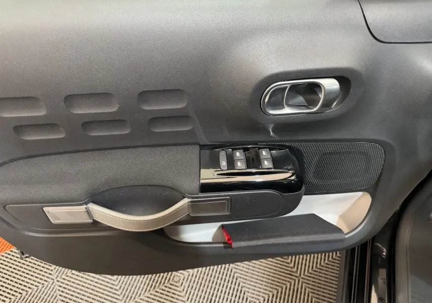 Vue rapprochée de la porte avant gauche noire d'une Citroën C3 2019, avec commandes de vitres et poignée intégrée.
