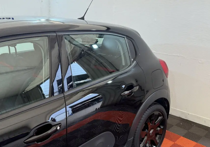 Vue latérale droite sur la partie arrière d'une Citroën C3 noire avec jantes noires et poignées de porte ton caisse.